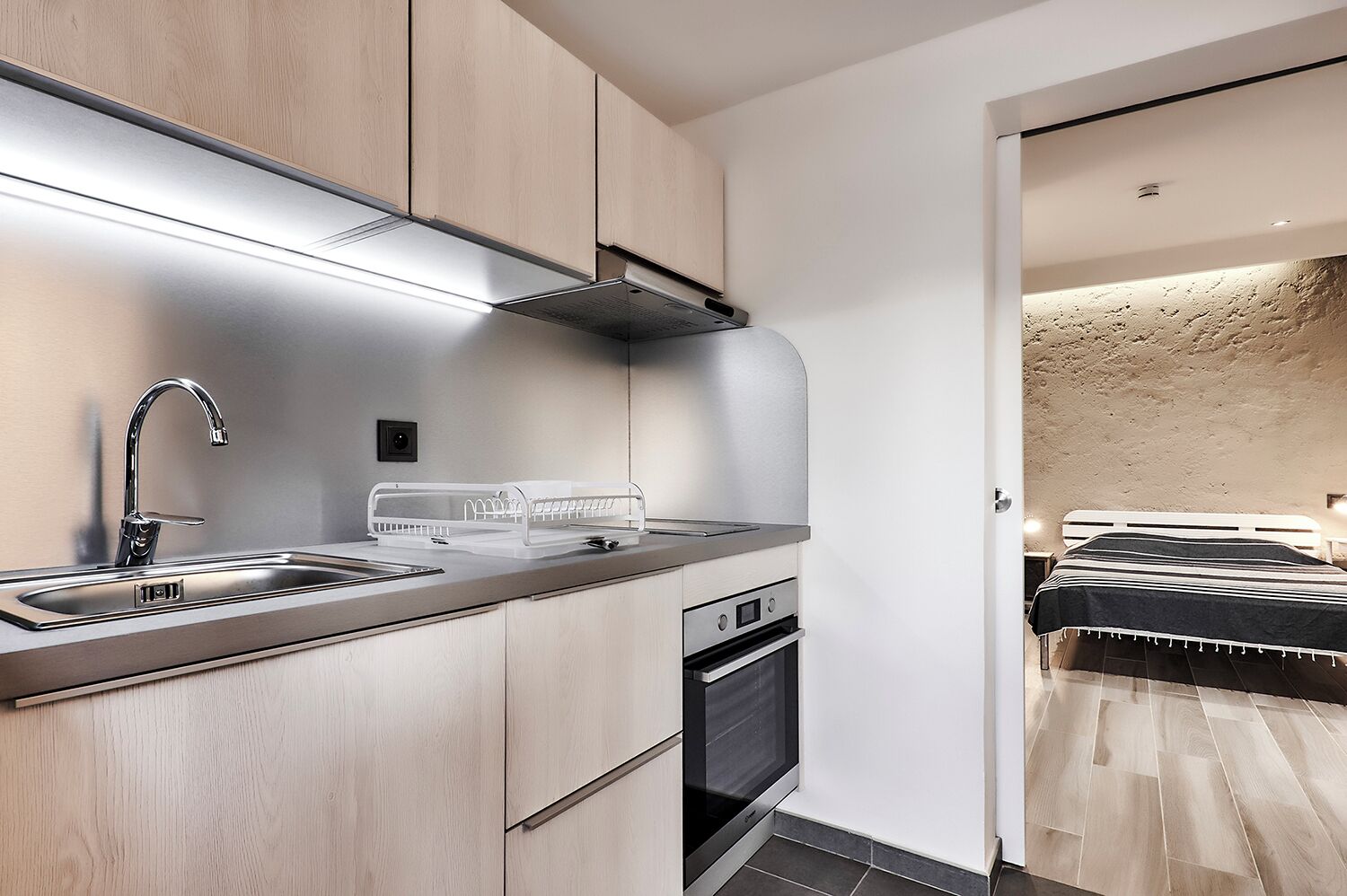 A modern kitchen with a stainless steel sink, a built-in oven, and a compact layout.