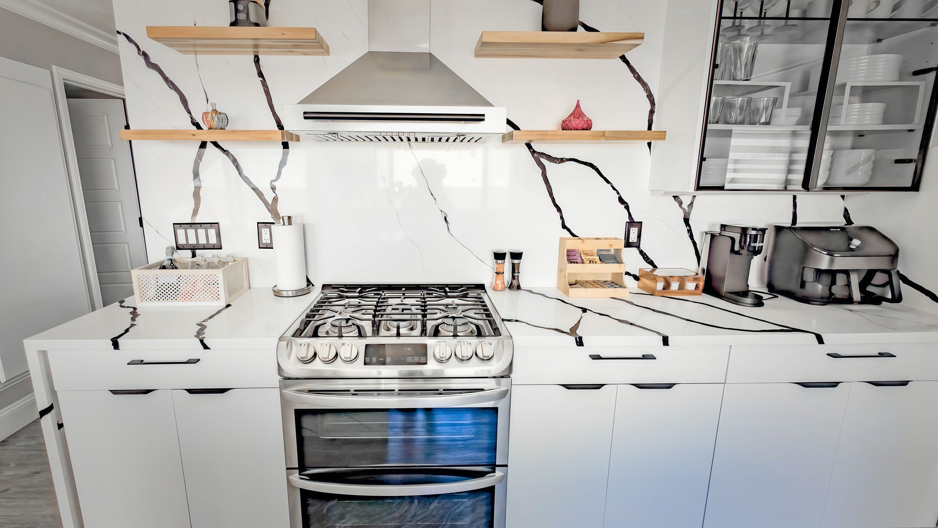A modern kitchen with white cabinetry, a stainless steel stove, and a built-in oven.