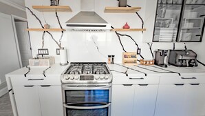 Une cuisine moderne avec des meubles blancs, une cuisinière en acier inoxydable et un four encastré.