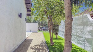 A narrow pathway leading to a building with a white exterior, a tree-lined area, and a clear sky. - Fully renovated and Spacious 4-bedroom 3 baths house (Upland)