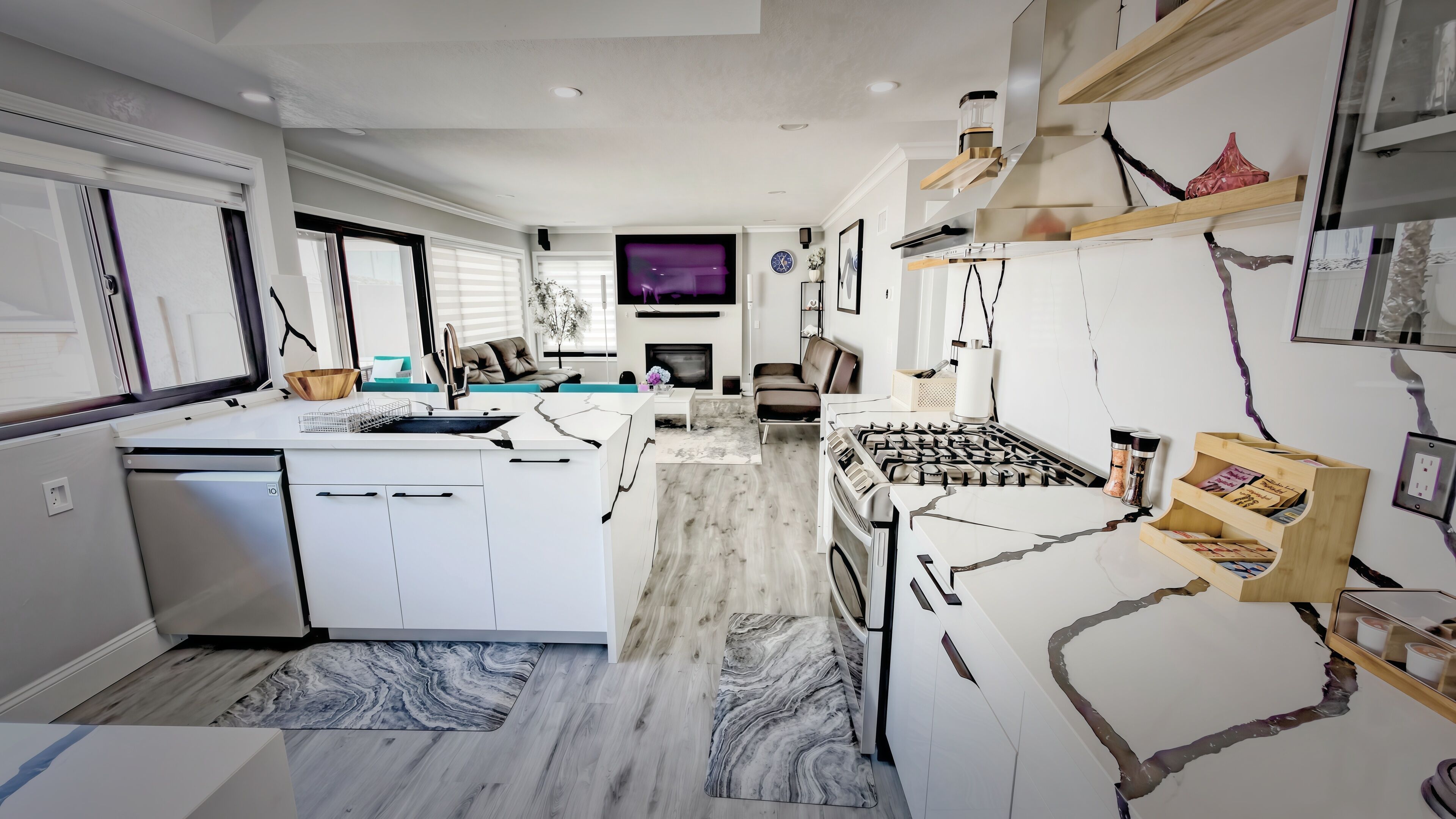 A modern kitchen with a central island, a dining area with a sofa, and a living room with a TV.