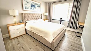 A hotel room with a large bed, bedside tables, a desk, and a window with curtains. - Fully renovated and Spacious 4-bedroom 3 baths house (Upland)