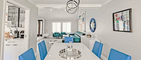 Un espace de salle à manger moderne avec une table blanche, des chaises bleues et un lustre original.
