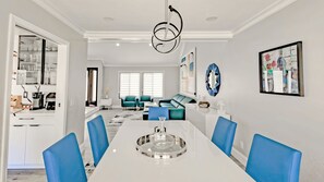 Un comedor moderno con una mesa blanca, sillas azules y una lámpara de techo original.