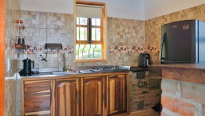 A kitchen with a stone backsplash, wooden cabinets, a built-in stove, and a refrigerator. - The Best View in the Region, Private Beach, Cabin (Pet-Friendly) (Boyacá)