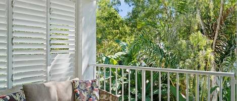 A balcony with a white railing, a sofa with cushions, and a small round table.