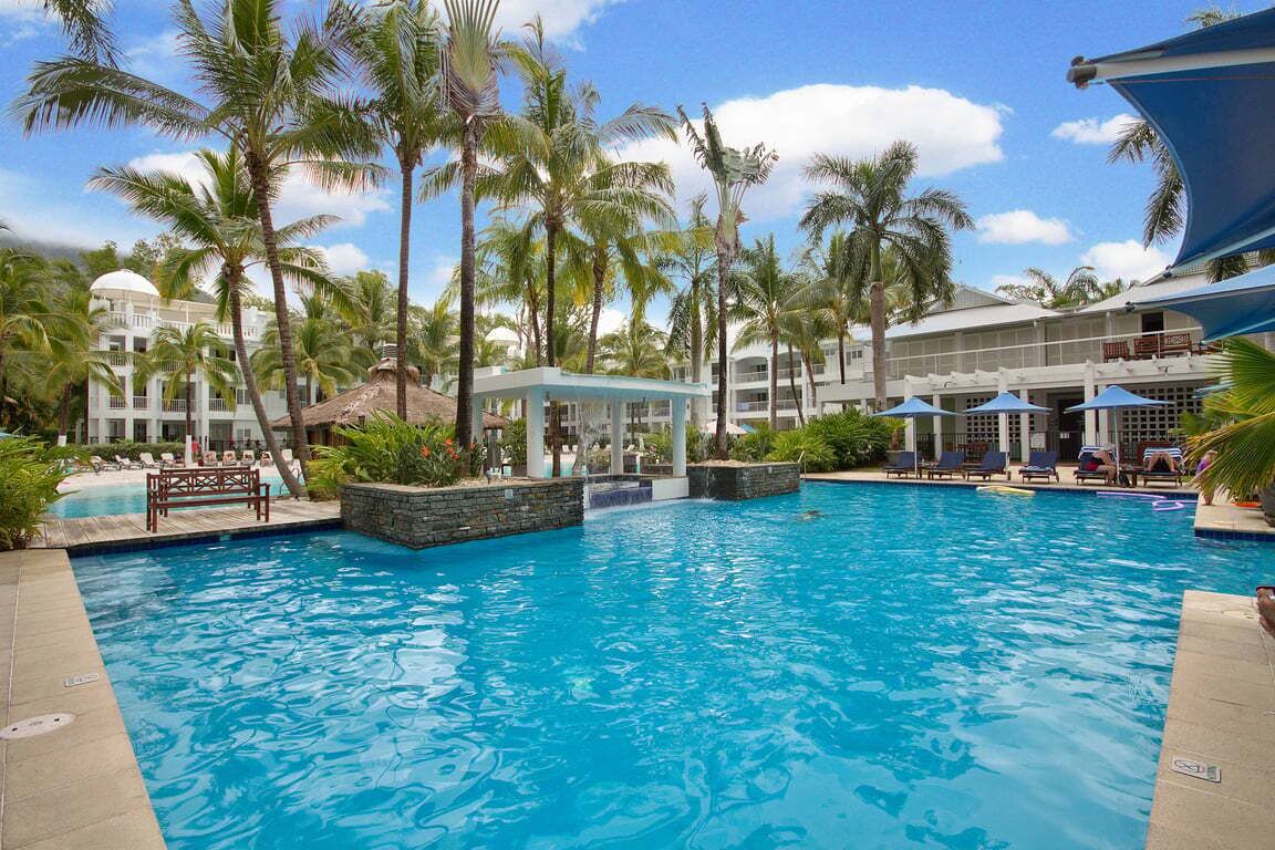 A swimming pool surrounded by palm trees and a building with a dome.