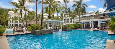 A swimming pool surrounded by palm trees and a building with a dome.