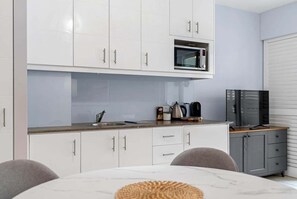 A modern kitchen with white cabinets, a microwave, and a coffee maker. - 3434 Peppers Spa Penthouse (Palm Cove)