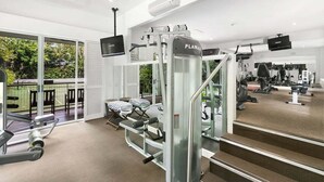 A gym with various exercise equipment, including a treadmill and weight machines, and a large window offering a view of the outdoors. - 3434 Peppers Spa Penthouse (Palm Cove)