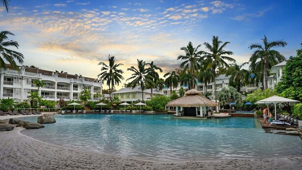 A resort with a large pool, palm trees, and beach chairs. - 3434 Peppers Spa Penthouse (Palm Cove)