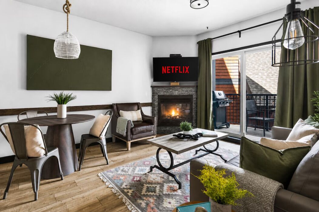 A modern living room with a fireplace, a television, and a dining area.