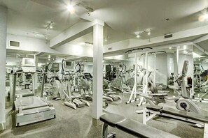 Een sportschool met diverse fitnessapparaten, waaronder loopbanden, hometrainers en krachtapparaten.
