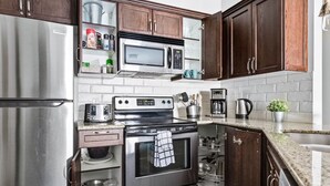 A modern kitchen with stainless steel appliances, wooden cabinets, and a white tiled backsplash. - Chic Twin Rockies Getaway - Pool&HotTub | Sleeps 8 (Canmore)