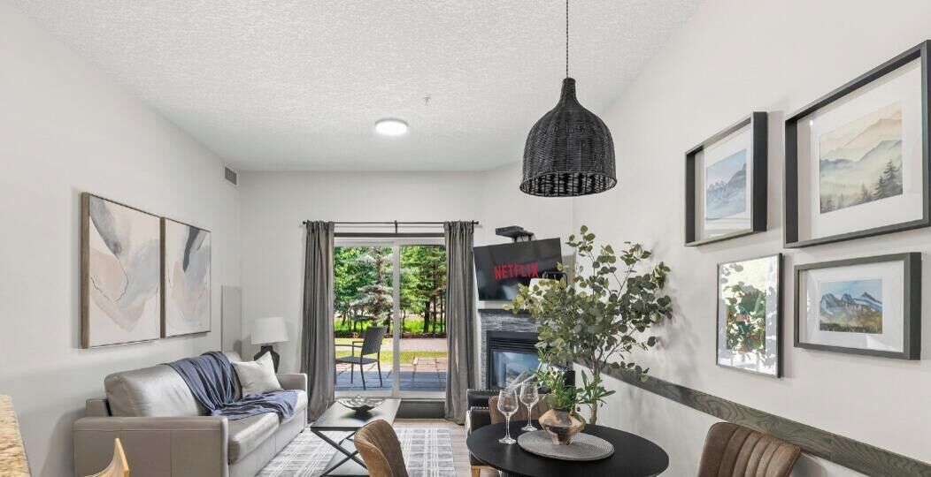 A modern living room with a sofa, dining table, and chairs, a television, and artwork on the walls.