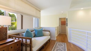 Ein Zimmer mit einer Couch, einem Holzschrank, einem gemusterten Teppich und Blick ins Freie.
