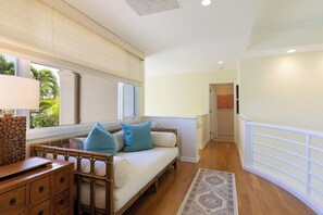A room with a sofa, a wooden dresser, a patterned rug, and a view of the outdoors. - The Islands at Mauna Lani - New Furnishings - Walk to beach and shops (Waimea)
