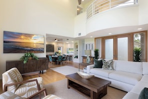 A spacious living area with a high ceiling, a dining area, and a kitchen. - The Islands at Mauna Lani - New Furnishings - Walk to beach and shops (Waimea)