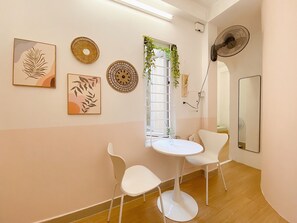 A room with a round table, two white chairs, a mirror, and wall art including leaf patterns and circular designs. - Group Stay for 4 • Big Beds • Hanoi Old Quarter Centre • Locker • Free Wash (Hà Nội)