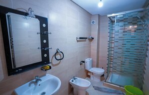 Ein Badezimmer mit Spiegel, Waschbecken, Bidet, Toilette und einer Duschkabine aus Glas.