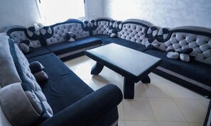 Ein modulares Sofa mit einer Noppenstruktur, ein Couchtisch in der Mitte und ein dunkel gefärbter Sessel.
