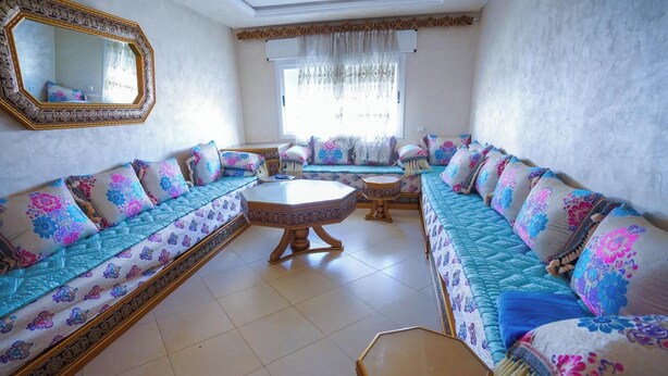 A living room with a sofa set, a coffee table, and a mirror. - Charming 2-bedroom Apartment With Shared Pool in Martil (Martil)