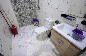 Um banheiro com vaso sanitário, pia e chuveiro.