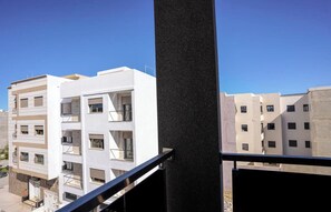 Um edifício residencial com vários andares, varandas, céu claro e guarda-corrimão preto.