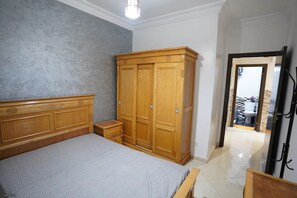 A bedroom with a bed, a wooden wardrobe, and a bathroom visible through an open door. - Charming 2 -bedroom Apartment in Martil, Morocco (Martil)