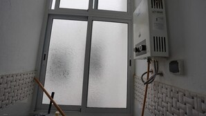 A room with a large frosted window, a radiator, and a wall-mounted air conditioning unit. - Charming 2 -bedroom Apartment in Martil, Morocco (Martil)