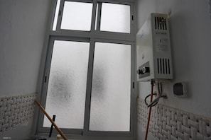 A room with a large frosted window, a radiator, and a wall-mounted air conditioning unit. - Charming 2 -bedroom Apartment in Martil, Morocco (Martil)