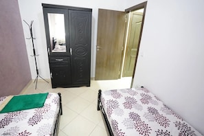 A room with two beds, a wardrobe, and a coat rack. - Charming 2 -bedroom Apartment in Martil, Morocco (Martil)