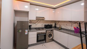 Eine kompakte Küche mit Einbauwaschmaschine, Mikrowelle und Kühlschrank.