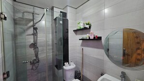 Un bagno moderno con doccia vetrata, un WC, un lavandino e uno specchio con cornice in legno.