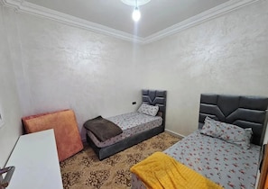 Ein Zimmer mit zwei Betten, einem Schreibtisch und einem gemusterten Teppich.
