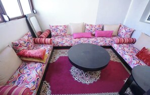 Ein gemütlicher Sitzbereich mit einer Sofagarnitur, einem runden Couchtisch und gemusterten Teppichen.
