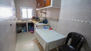 A compact kitchen with a sink, stove, and cabinets. - Charming 1-bedroom Apartment With City View in Martil (Martil)