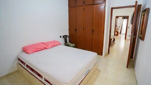 A bedroom with a bed, a wardrobe, and a door leading to another room. - Charming 1-bedroom Apartment With City View in Martil (Martil)