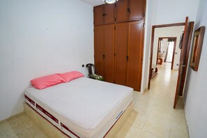 A bedroom with a bed, a wardrobe, and a door leading to another room. - Charming 1-bedroom Apartment With City View in Martil (Martil)