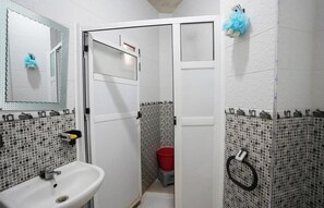 A bathroom with a white sink, a mirror, a door, and a red bucket. - Charming 1-bedroom Apartment With City View in Martil (Martil)