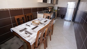 Uma cozinha compacta com mesa, cadeiras e geladeira.