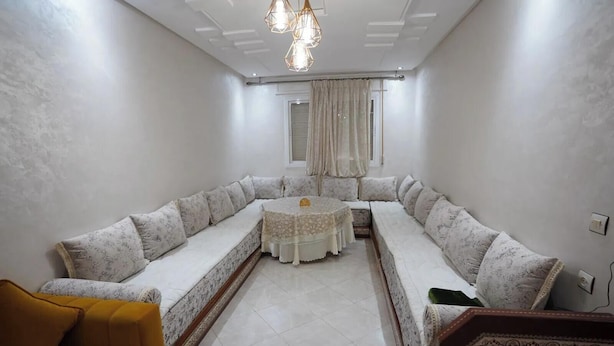 Uma sala de estar moderna com um amplo sofá em formato de L, uma mesa de centro redonda e uma poltrona amarela.