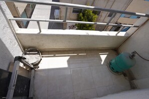 A balcony with a metal railing, a water pipe, and a green gas cylinder. - Charming Accessible Apartment in Martil, Morocco (Martil)
