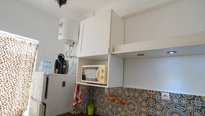 A kitchen with a refrigerator, a kettle, and a microwave. - Charming 2-bedroom Apartment in Martil, Morocco (Martil)