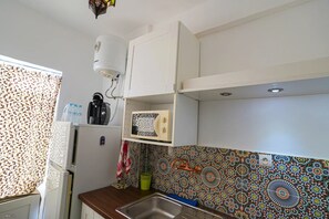 Eine Küche mit einem Kühlschrank, einem Wasserkocher und einer Mikrowelle.