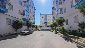 A street with buildings on either side, a parked car, and a clear sky. - Charming 2-bedroom Apartment in Martil, Morocco (Martil)