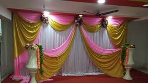 A stage with draped curtains and floral arrangements. - Hotel Rama Palace (Nashik)