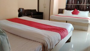 A hotel room with two beds, a wardrobe, and a seating area. - Hotel Rama Palace (Nashik)