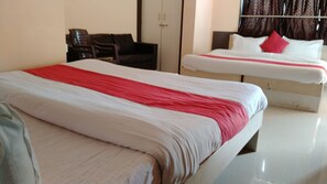 A hotel room with two beds, a wardrobe, and a seating area.