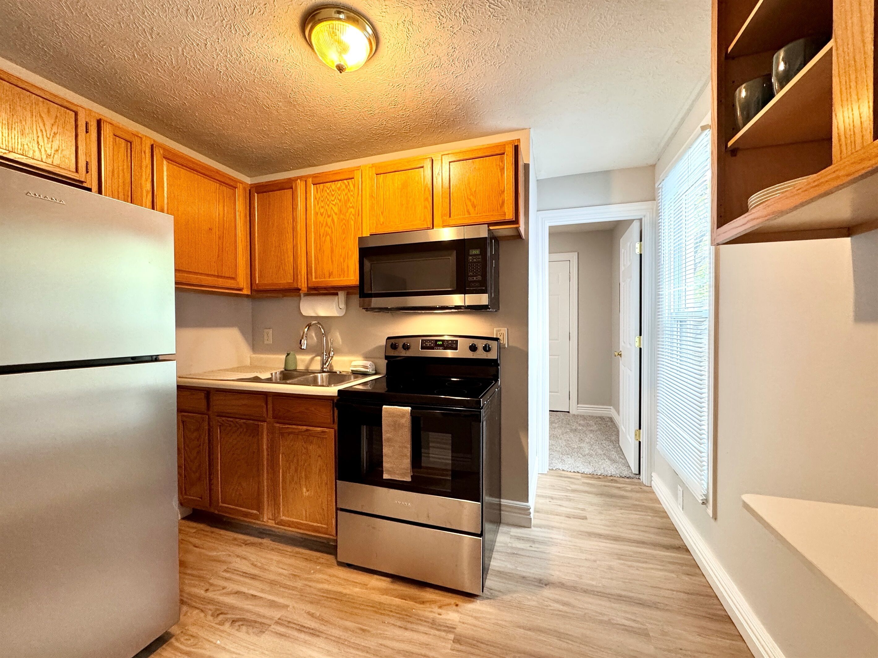 A kitchen with wooden cabinets, stainless steel appliances, and a microwave.
